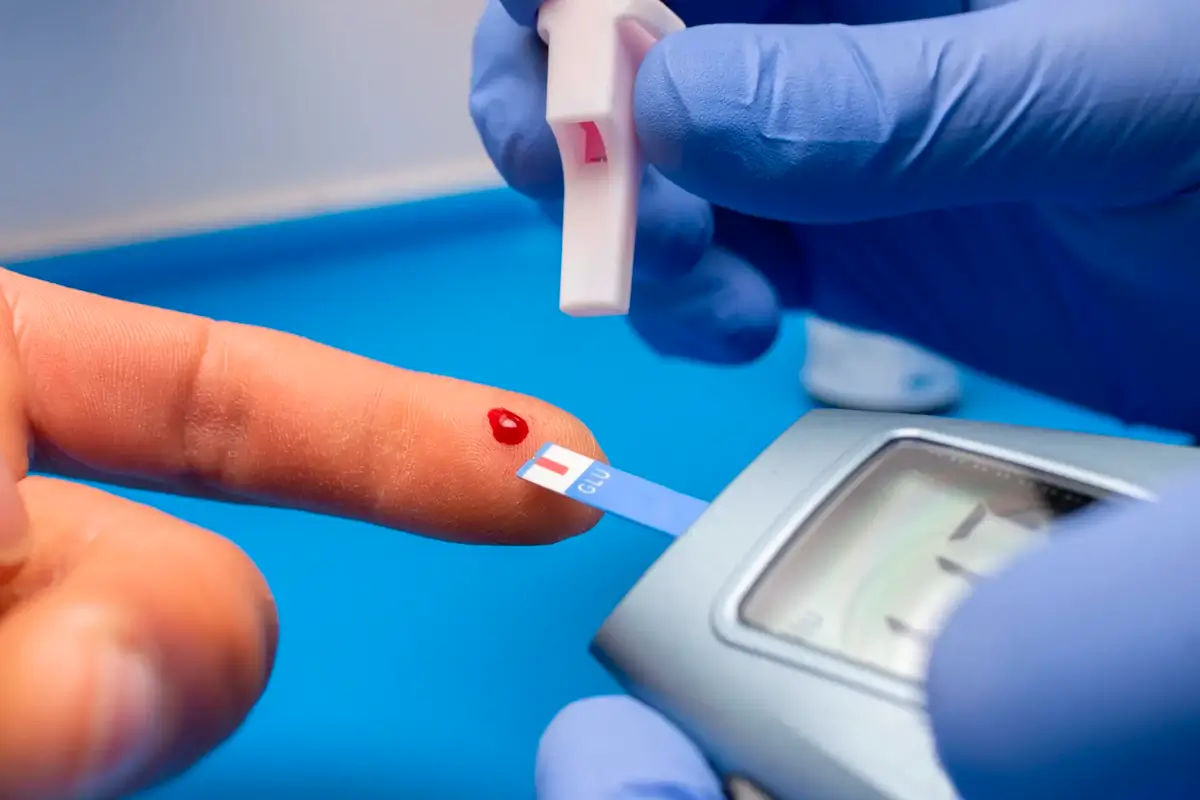 Persona midiendo el azúcar con un glucómetro, ilustrando la importancia de monitorear los niveles de glucosa para la salud.